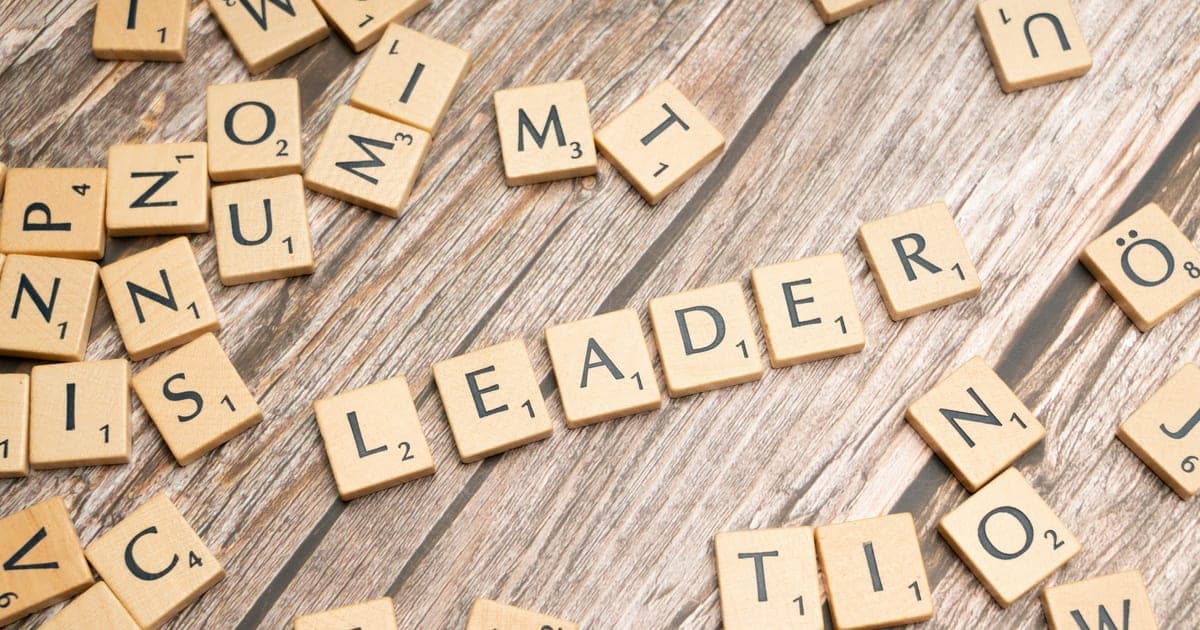 Scrabble tiles spelling out the word leader in a word